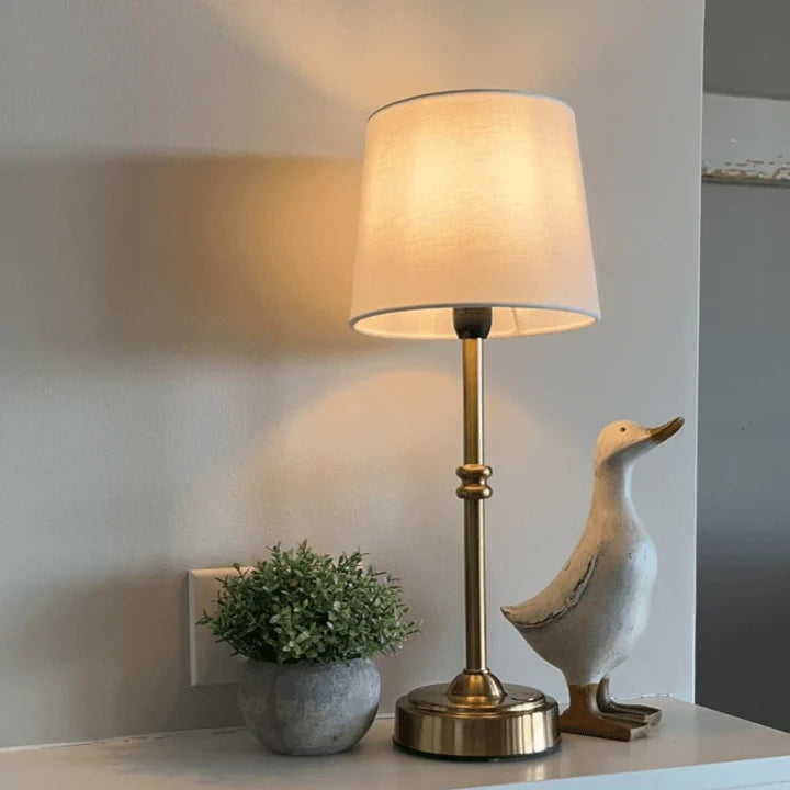 Cordless LED table lamp with fabric shade on a shelf in an apartment