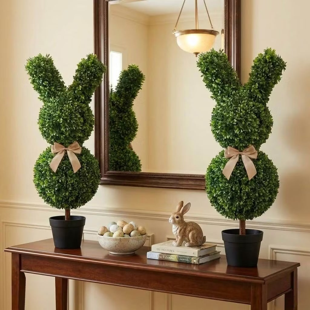 Set of two 36-inch artificial Easter bunny topiaries with green foliage and champagne bows on a porch