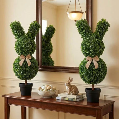 Set of two 36-inch artificial Easter bunny topiaries with green foliage and champagne bows on a porch