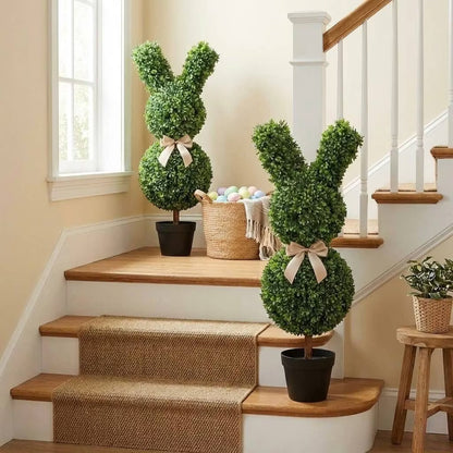 Set of two 36-inch artificial Easter bunny topiaries with green foliage and champagne bows on a porch