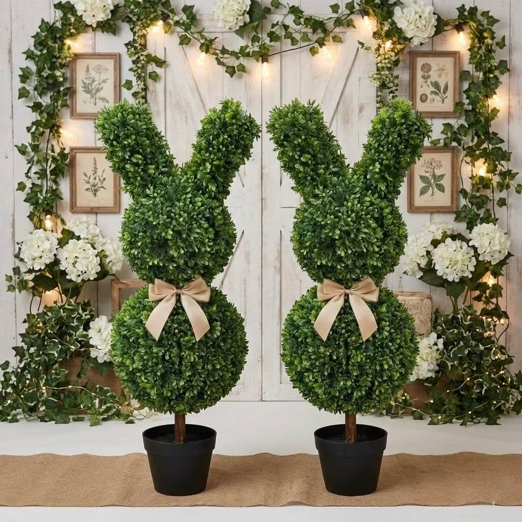 Set of two 36-inch artificial Easter bunny topiaries with green foliage and champagne bows on a porch