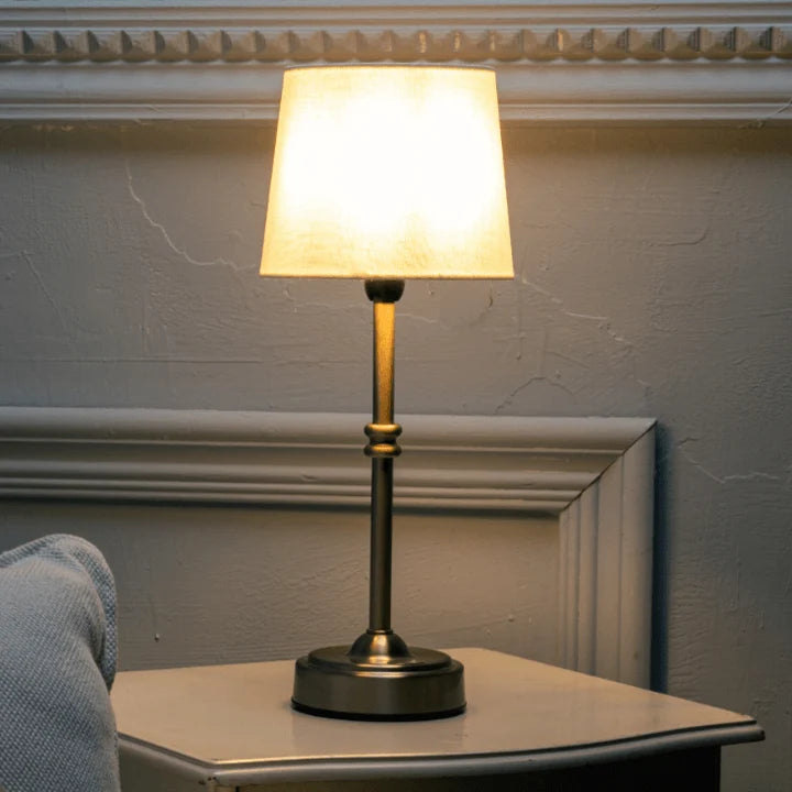 Cordless LED table lamp with fabric shade on a shelf in an apartment