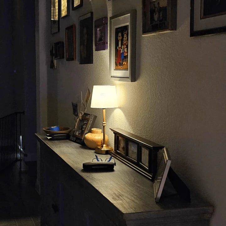 Cordless LED table lamp with fabric shade on a shelf in an apartment