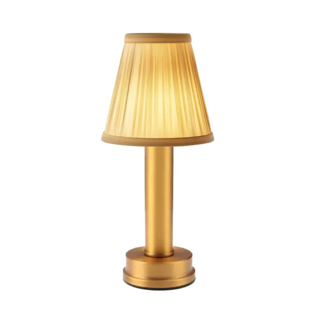 Cordless brass table lamp with fabric shade on a wooden table, portable for home decor
