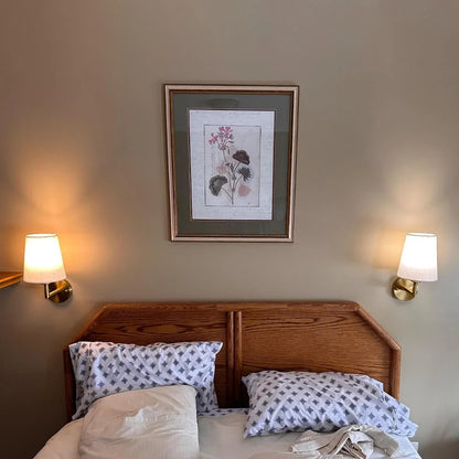 Wireless fabric wall sconce with metal accents, mounted on a wall, for renters