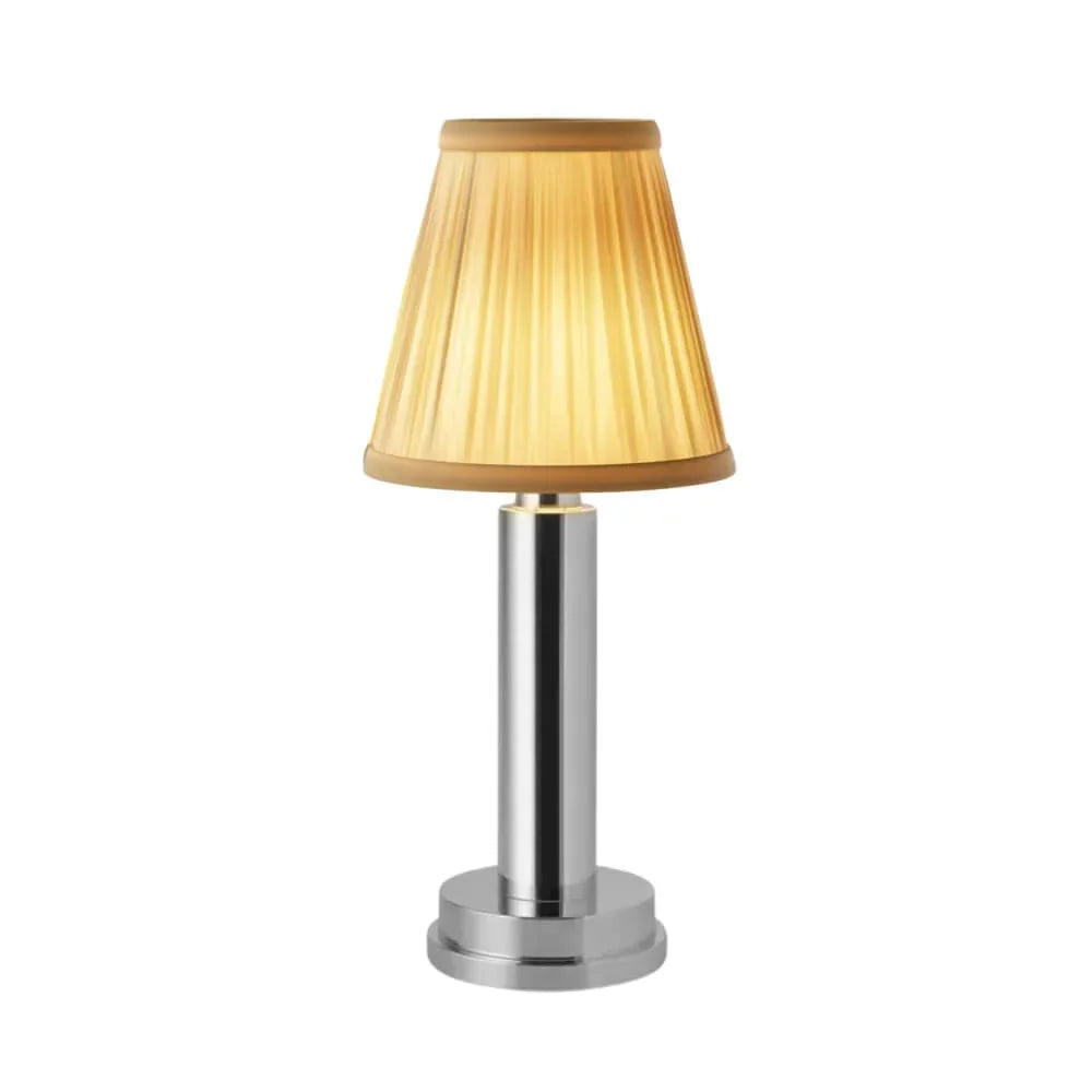 Cordless brass table lamp with fabric shade on a wooden table, portable for home decor