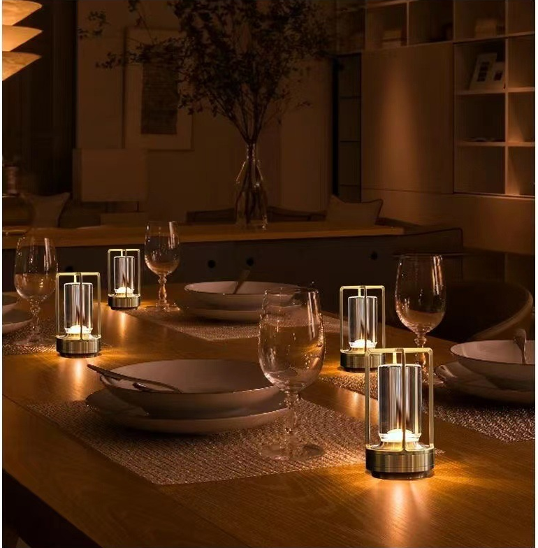 Cordless table lamp with metal cage and warm glow on a camping table