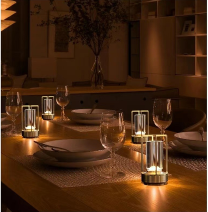 Cordless table lamp with metal cage and warm glow on a camping table