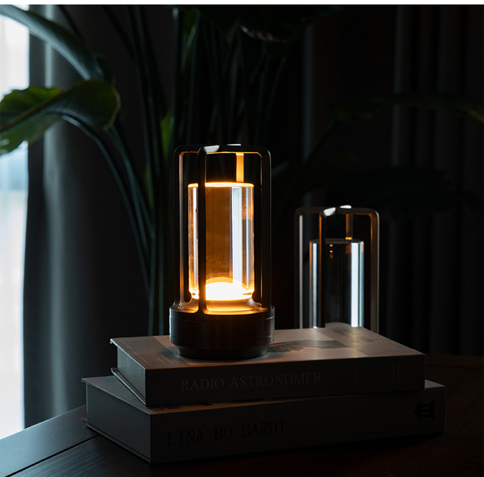 Cordless table lamp with metal cage and warm glow on a camping table
