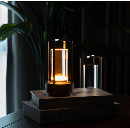 Cordless table lamp with metal cage and warm glow on a camping table