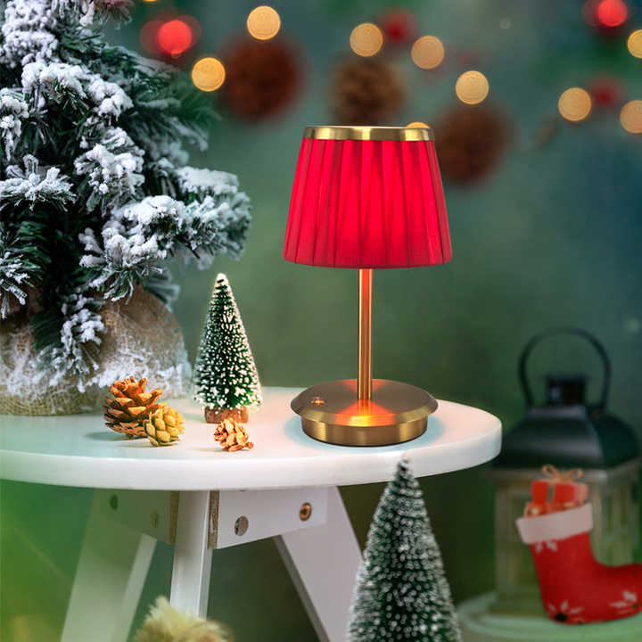 Cordless rechargeable table lamp with gold frame and fabric shade on a desk