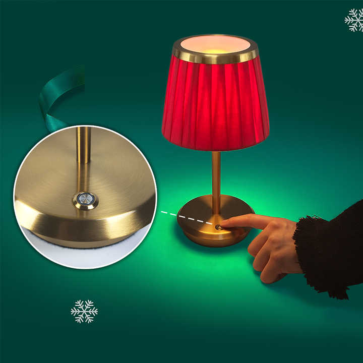 Cordless rechargeable table lamp with gold frame and fabric shade on a desk