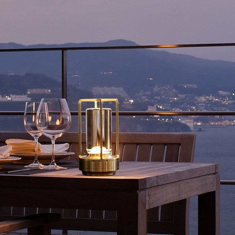 Cordless table lamp with metal cage and warm glow on a camping table