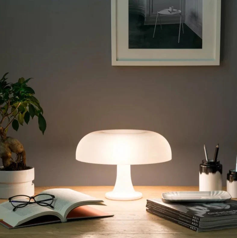 Mushroom-shaped acrylic table lamp with a warm glow on a bedside table