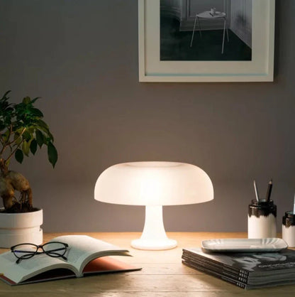Mushroom-shaped acrylic table lamp with a warm glow on a bedside table
