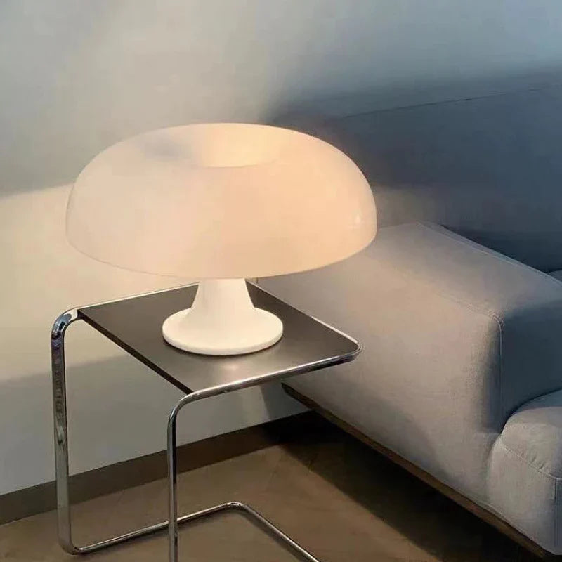 Mushroom-shaped acrylic table lamp with a warm glow on a bedside table