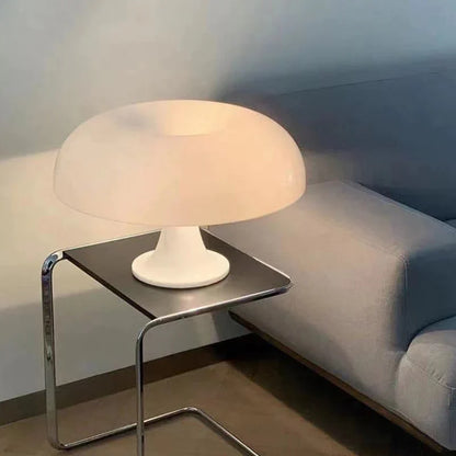 Mushroom-shaped acrylic table lamp with a warm glow on a bedside table