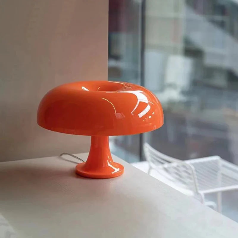 Mushroom-shaped acrylic table lamp with a warm glow on a bedside table