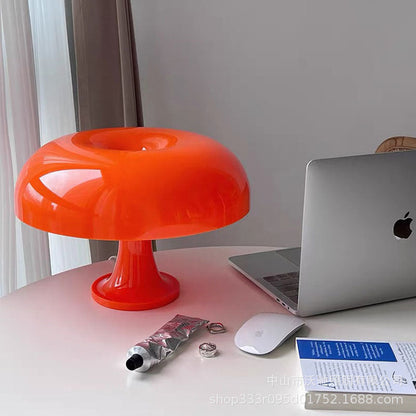 Mushroom-shaped acrylic table lamp with a warm glow on a bedside table