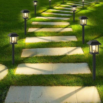 Edison-style solar lawn lights glowing along a garden path at dusk