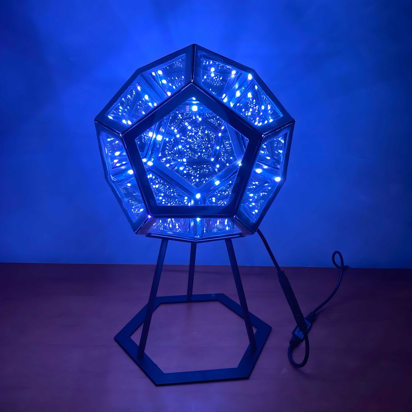 3D infinity mirror dodecahedron night light with rainbow LED glow on a wall, creating a photo backdrop for parties