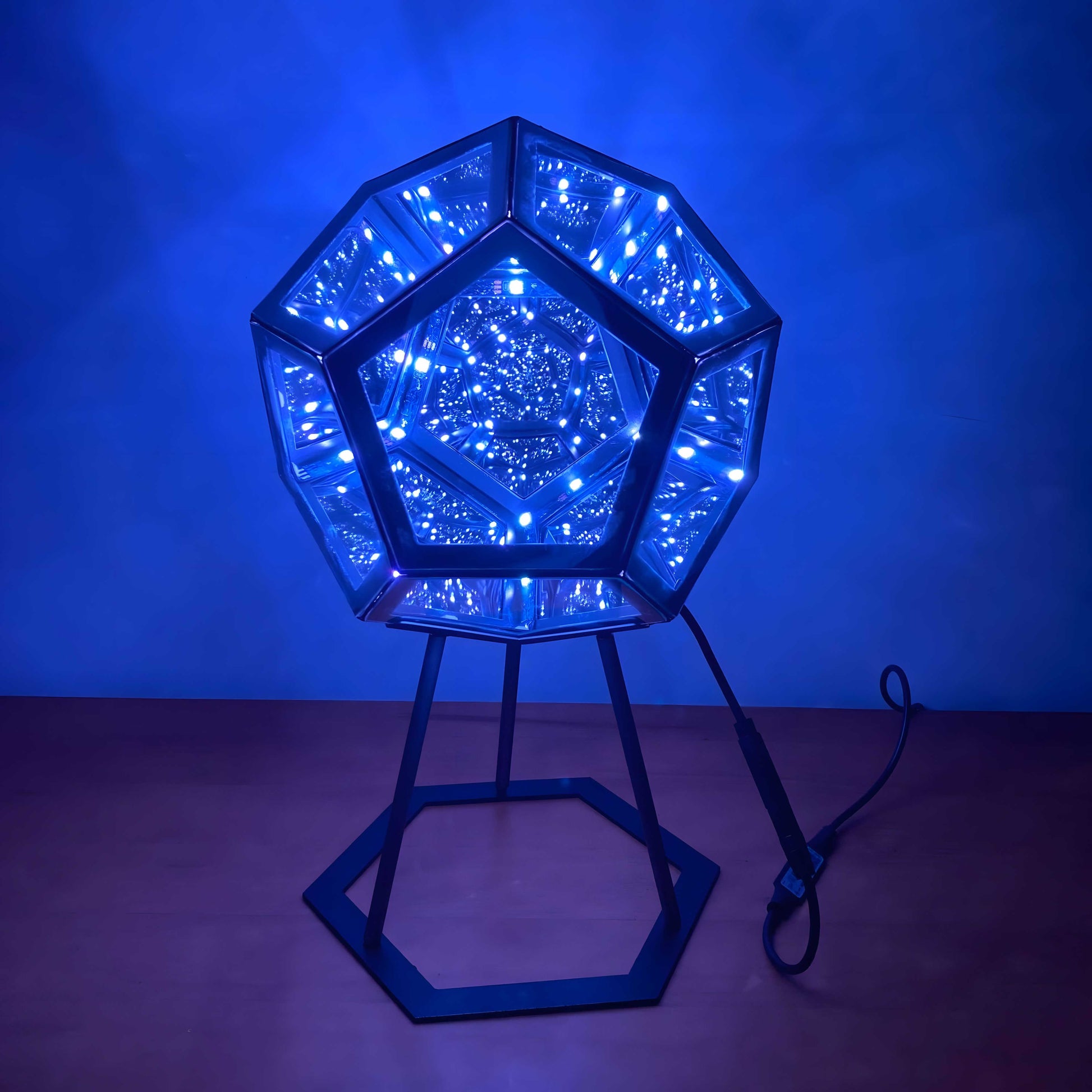 3D infinity mirror dodecahedron night light with rainbow LED glow on a wall, creating a photo backdrop for parties