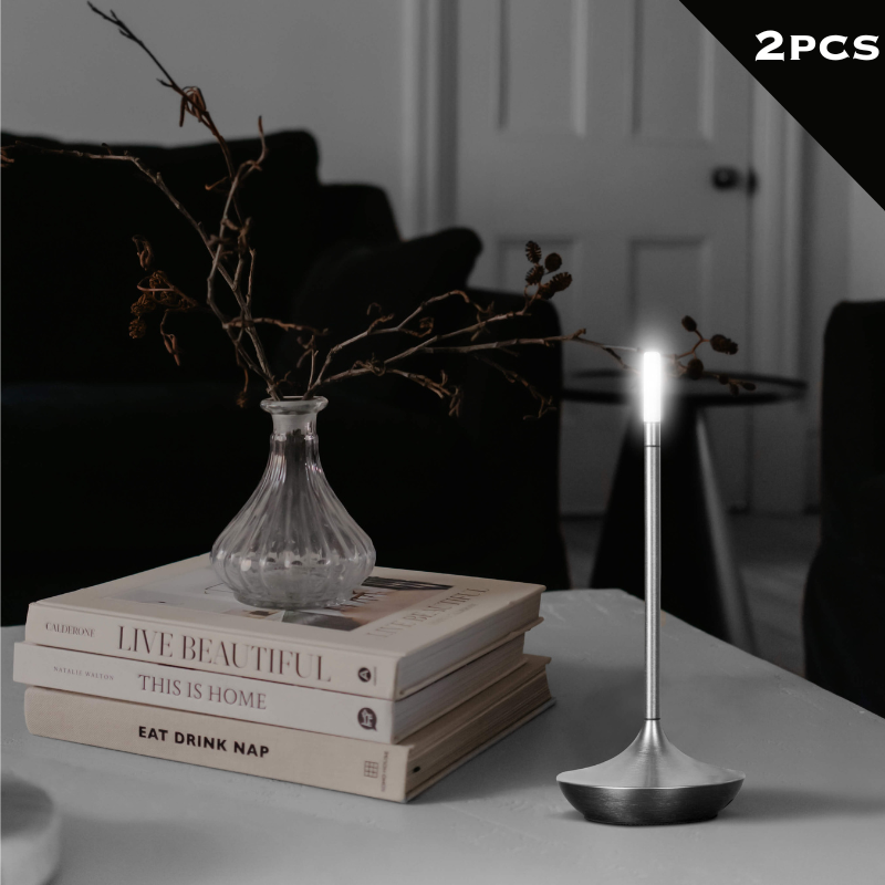 Rechargeable LED candle lamp with brass finish and carrying ring, glowing warmly on a table