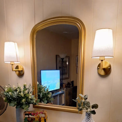 Wireless fabric wall sconce with metal accents, mounted on a wall, for renters