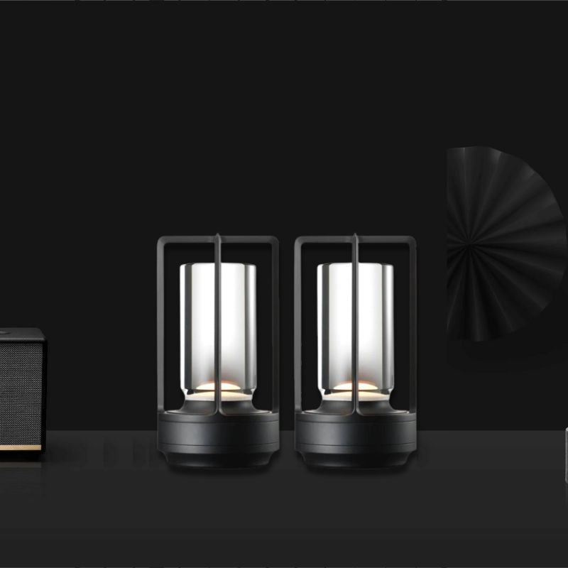 Cordless table lamp with metal cage and warm glow on a camping table