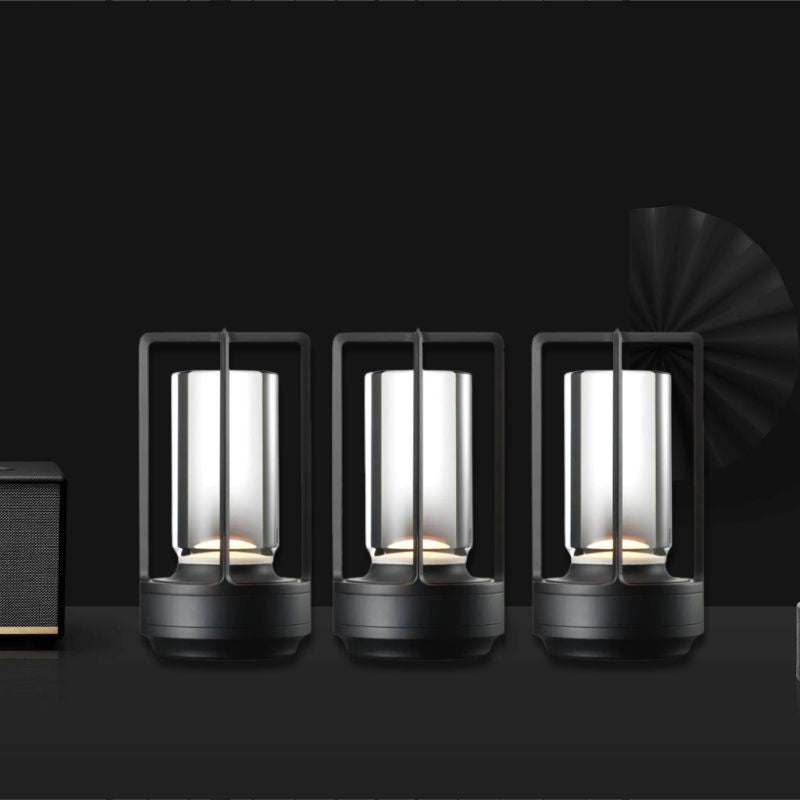Cordless table lamp with metal cage and warm glow on a camping table