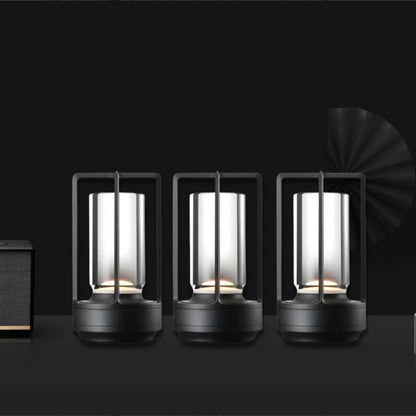 Cordless table lamp with metal cage and warm glow on a camping table