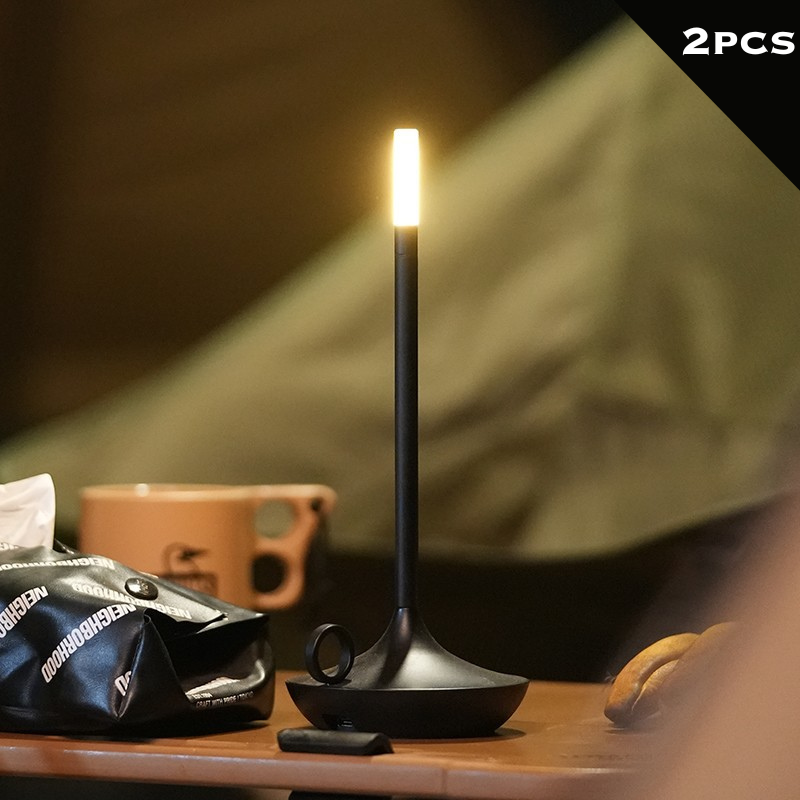 Rechargeable LED candle lamp with brass finish and carrying ring, glowing warmly on a table