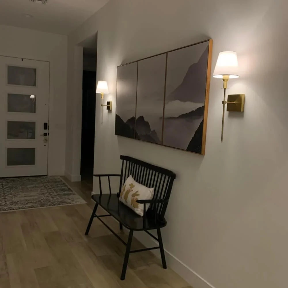 Rechargeable wireless wall sconce with metal and cloth shade, mounted on a wall in a living room, no cords visible