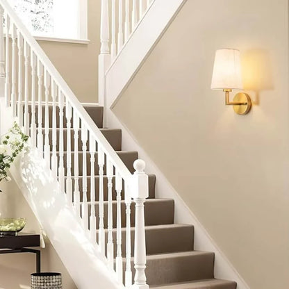 Wireless fabric wall sconce with metal accents, mounted on a wall, for renters