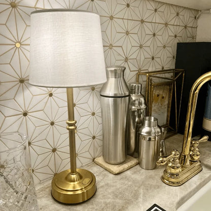 Cordless LED table lamp with fabric shade on a shelf in an apartment