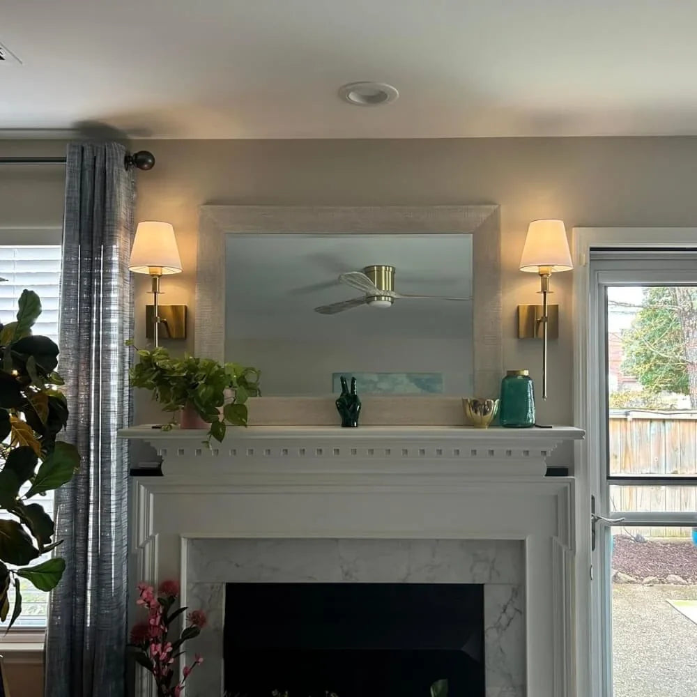 Rechargeable wireless wall light with metal accents, mounted on a wall in a living room, for renters