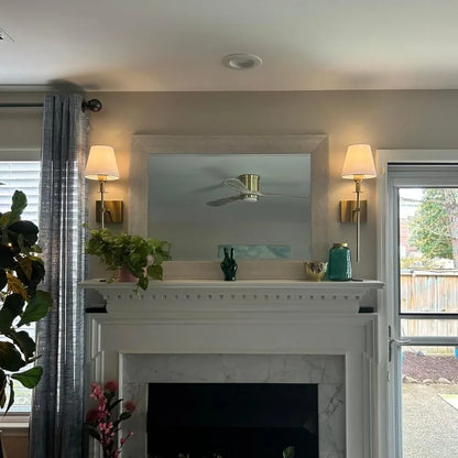 Rechargeable wireless wall sconce with metal and cloth shade, mounted on a wall in a living room, no cords visible