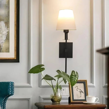 Rechargeable wireless wall light with metal accents, mounted on a wall in a living room, for renters