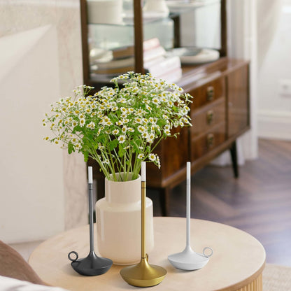 Rechargeable LED candle lamp with brass finish and carrying ring, glowing warmly on a table