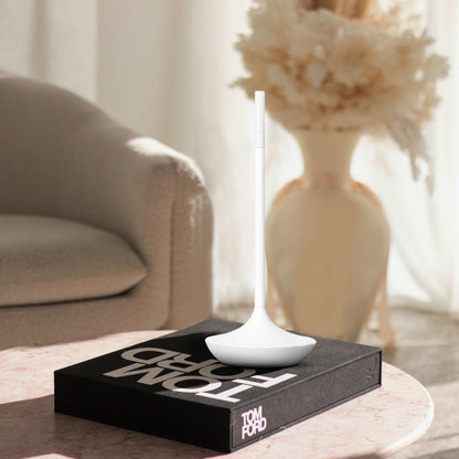 Rechargeable LED candle lamp with brass finish and carrying ring, glowing warmly on a table