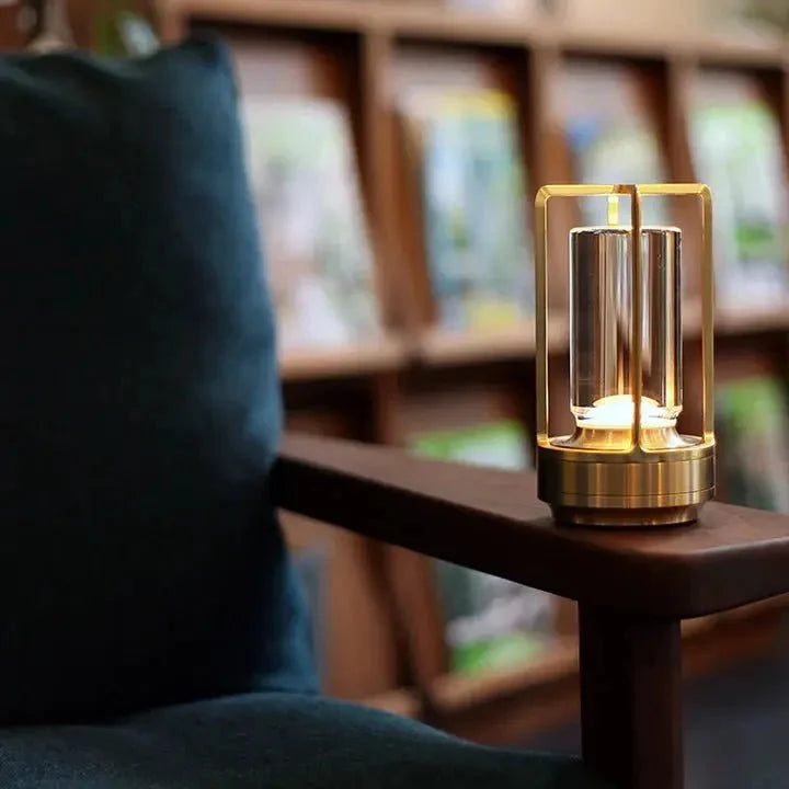 Cordless table lamp with metal cage and warm glow on a camping table