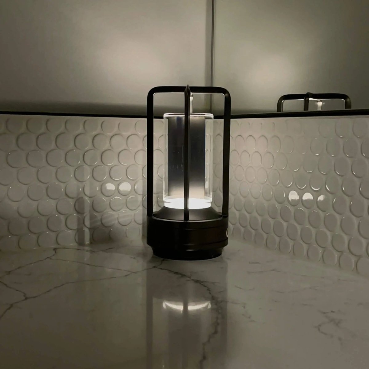 Cordless table lamp with metal cage and warm glow on a camping table