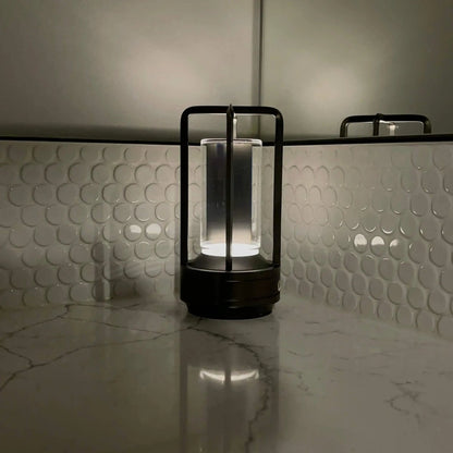 Cordless table lamp with metal cage and warm glow on a camping table
