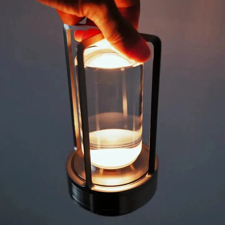 Cordless table lamp with metal cage and warm glow on a camping table