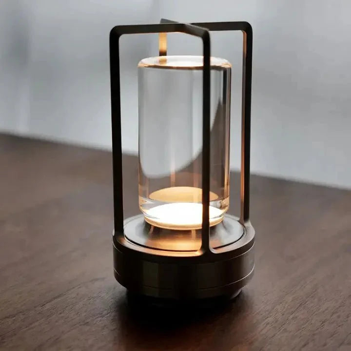 Cordless table lamp with metal cage and warm glow on a camping table