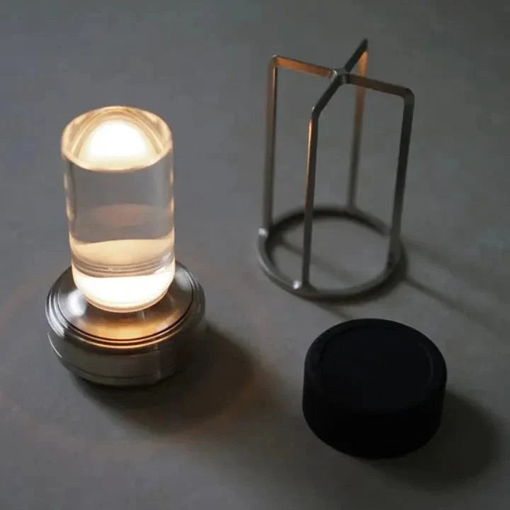 Cordless table lamp with metal cage and warm glow on a camping table