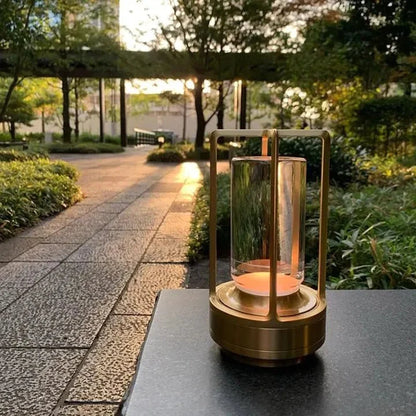 Cordless table lamp with metal cage and warm glow on a camping table