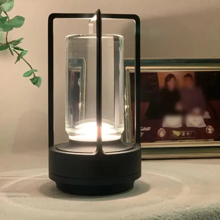 Cordless table lamp with metal cage and warm glow on a camping table