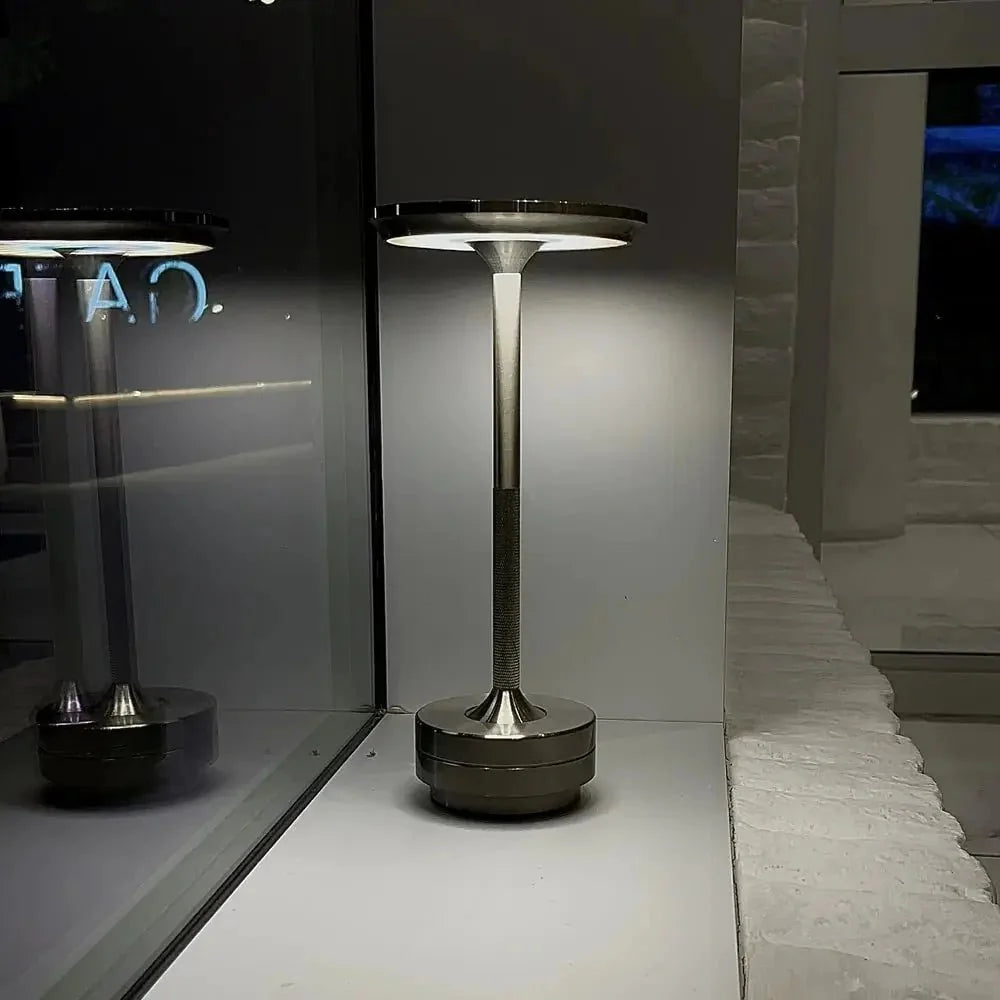 Cordless table lamp with aluminum body on an outdoor dining table