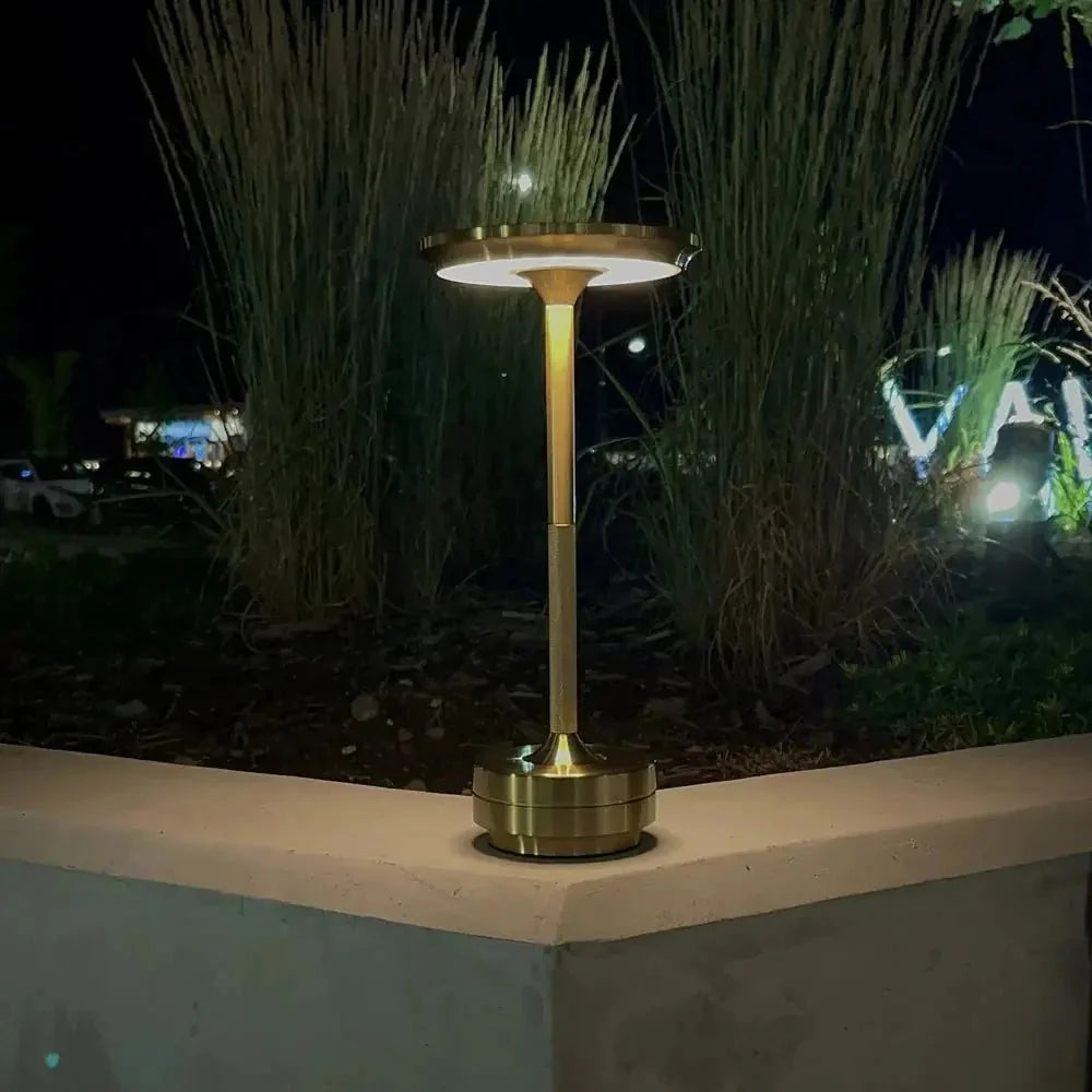 Cordless table lamp with aluminum body on an outdoor dining table